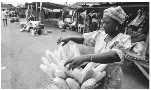 A woman selling baguettes at a market in Cotonou. Many Beninese homes lack refrigeration, necessitating almost daily trips to the marketplace.