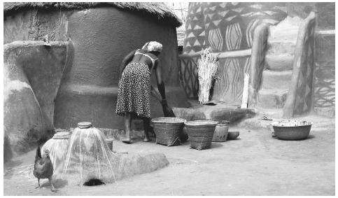 A Burkinabè woman sweeping her compound kitchen. Men and women have equal responsibilties in the agricultural sector of rural areas.