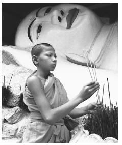 A young Cambodian monk burning incense. Monkhood offers a means to education for boys in Cambodia.