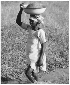 A woman carrying water back to her home to help care for and feed her family.