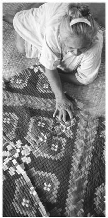 A woman sits on the floor making a colorful quilt in the city of Aitutaki.