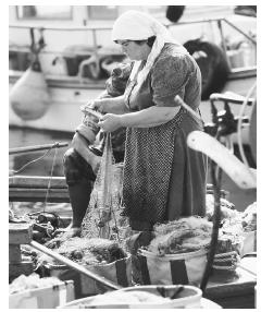 A man and woman repair fishing nets in a boat in Paphos, Cyprus.