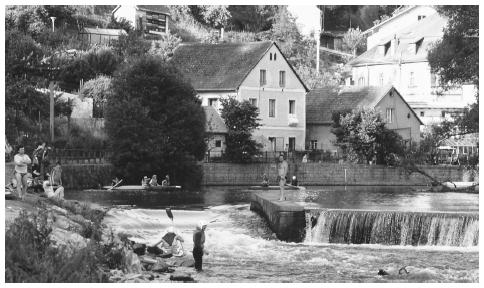 People relax by the river in the picturesque town of Rožmberk.
