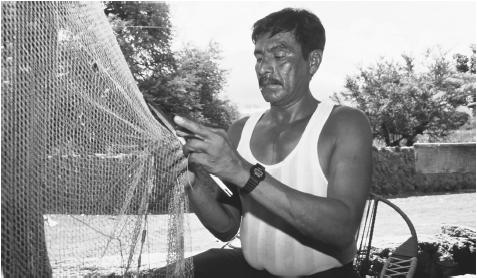 A Salvadoran man works on his fishing net. Many Salvadorans are employed in low-paying, "informal economy" jobs.