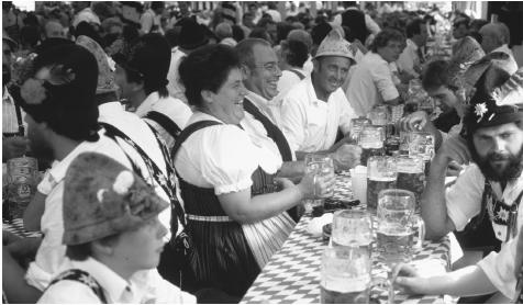 People socializing at a festival in Allgau. German beer, a favorite beverage, must be made only of water, hops, and malt.