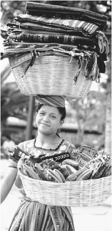 A woman carries baskets of textiles along a street in Antigua. Guatemalan textiles are highly regarded for their quality.