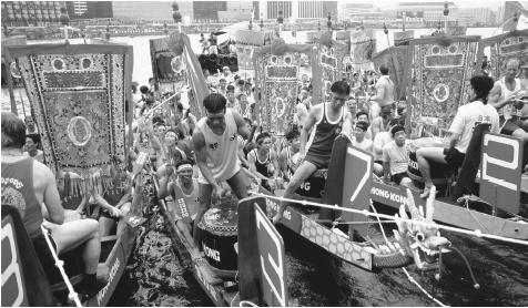 Crew members prepare to race in the Dragon Boat Festival while  drummers beat their drums. The Dragon Boat Festival is held annually in  June in Hong Kong.