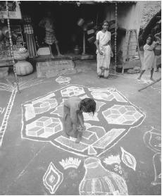 A woman decorates the streets with vibrantly colored rice powder paintings during a festival in Madurai, India.