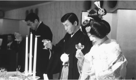 A Japanese bride and groom hold their champagne glasses during a traditional Shintō wedding ceremony. Japanese weddings are elaborately staged and usually held in banquet halls or hotels.