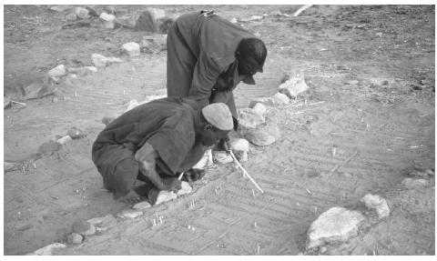 Two Dogon people perform a divination ritual using the prints left in the sand by a jackal. An estimated 19 percent of Mali's population follows traditional religious practices.