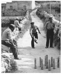 Men play brilli, a form of bowling often called ninepins, on a narrow street in Gozo, Malta.