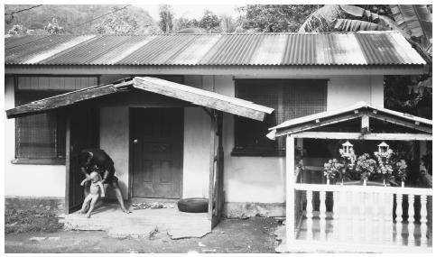 A man with a small child in front of his house in Kolonia, Pohnpei, Caroline Islands. Fathers and mothers equally tend to children in Micronesian society.
