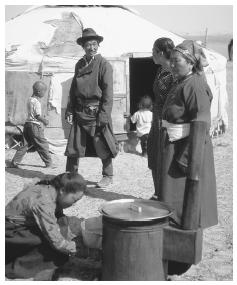Mongolian nomads cook at a stove outside a yurt. Meat and dairy products are a predominant staple of the diet.