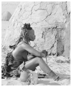 Himba woman next to a mud hut at a Nomadic People Camp in the Skeleton Coast. Namibia was originally inhabited by nomadic hunters, gatherers, and pastoralists.