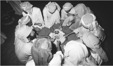 A group of Bedouin eat a meal. Omani cuisine revolves around rice.