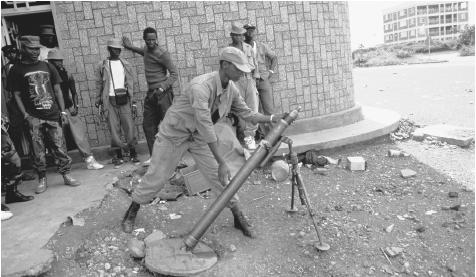 A member of the RFP loads a mortar as crowds watch the frontline. The Rwandan political system is dominated by the military.