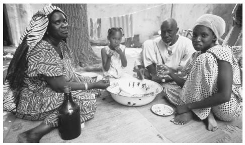 A Senegalese family having a meal together, Ile de Goree. Traditional housekeeping and child-rearing roles are expected from Senegalese women, particularly in rural areas.