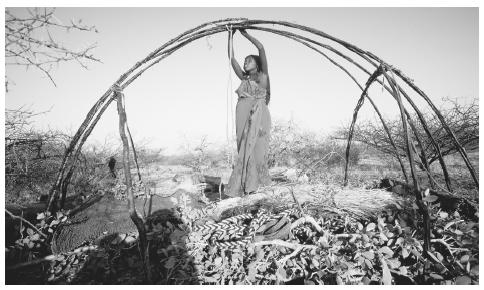 A Somali nomad woman ties roof supports together to reconstruct a portable hut after moving to a new location. The aqal is easy to break down and reassemble.