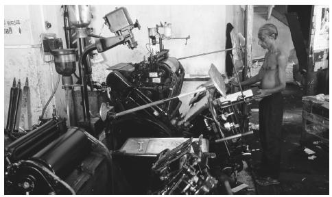 A man operates a Heidelburg printing press at a printer shop in Sri Lanka.