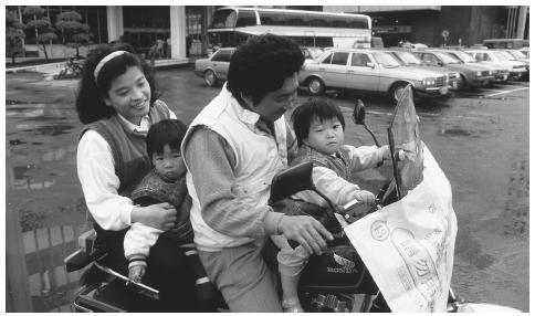 A family rides a motorcycle in Taipei, Taiwan, which is a common mode of transportation.