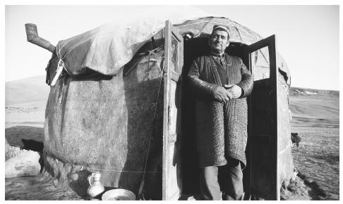 A man stands in the doorway of a yurt in a desolate area in the western Pamirs.