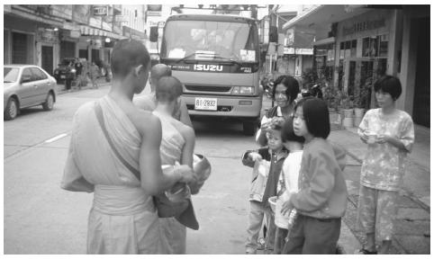 Buddhist monks walk down a street in Thailand. Most young men become Buddhist novices.