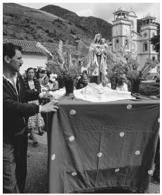 Parishioners push a portable shrine past a church during a  festival. Most Venezuelans practice Catholicism.