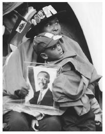 Two Haitian Americans hold a photo of deposed Haitian president Jean-Bertrand Aristide while listening to Aristide speak in New York City in 1992. Arisitide returned to Haiti as president in 1994.