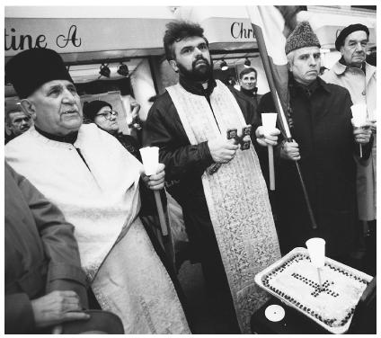 In this 1992 photograph, Romanian priests lead a service outside the Romanian mission to the United Nations to commemorate the anniversary of the Romanian Revolution. In the foreground is the traditional sweet dish known as colvia.