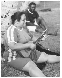 A Samoan American woman plays the ukulele at a family picnic on Queen's Beach, Honolulu, Hawaii