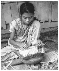 A young girl makes matchboxes in the slums of Khulna. There is a marked split between rich and poor in most of the country.