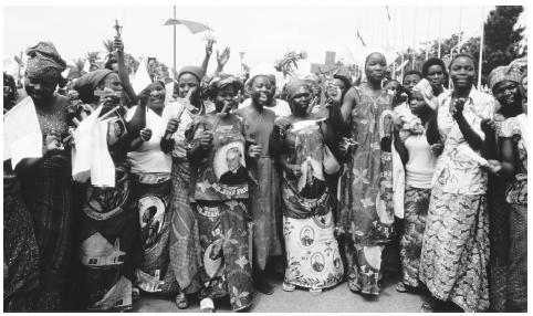 A group of women holding papal flags and wooden crosses on the streets of Congo.