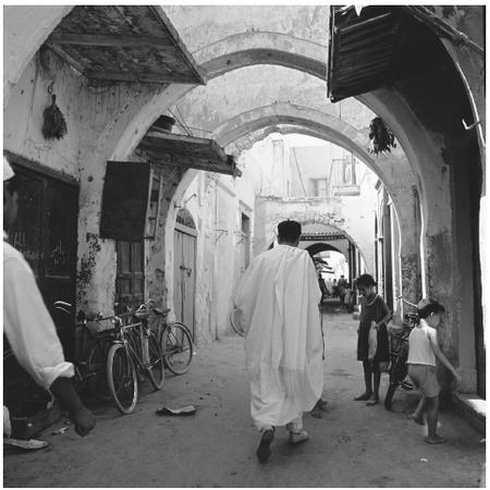 A man walking along a covered street in Tripoli. Walled fortifications dominate the old section of the city.