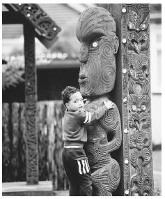 A boy and a wooden Maori sculpture. Maori tribes were among New Zealand's first settlers.
