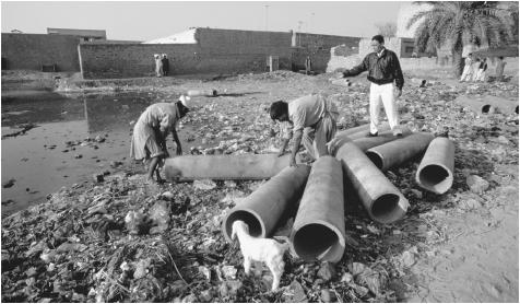 Workers on a community sanitation project examine the pipes for a new sewer in Faisalabad.