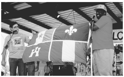 These two men are presenting the Creole flag to the audience at a Creole festival.
