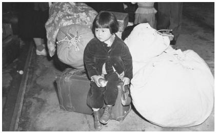 This small girl awaits instructions as to where she and her family are to be interned during World War II.