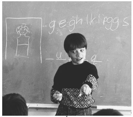 Russian American immigrant Olesa Zaharova leads a game of hangman on the blackboard of her language class.